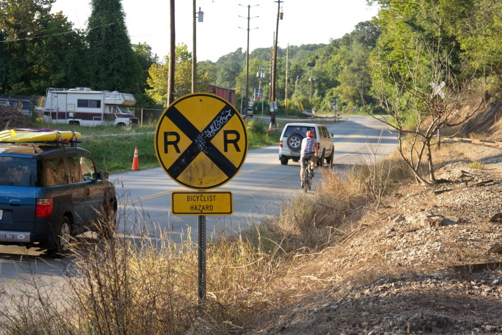 Cyclist surrounded by cars approaching railroad crossing