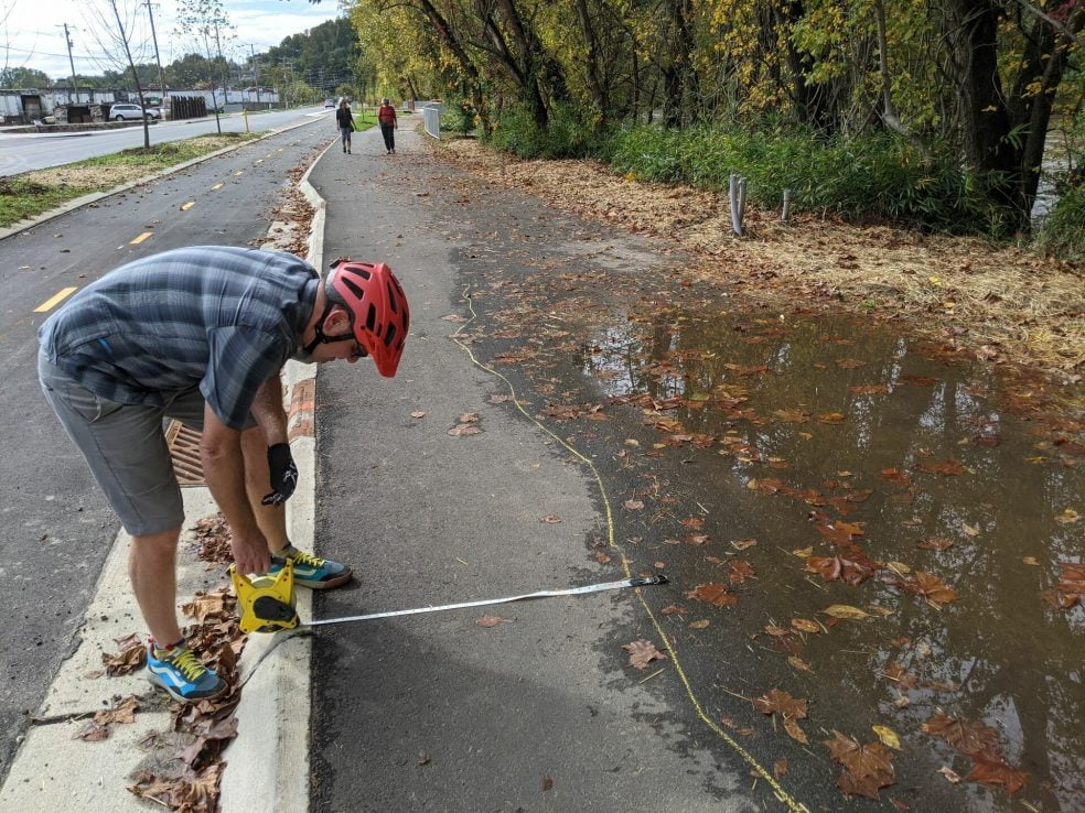 Large water puddle on greenway with Mike Sule measuring