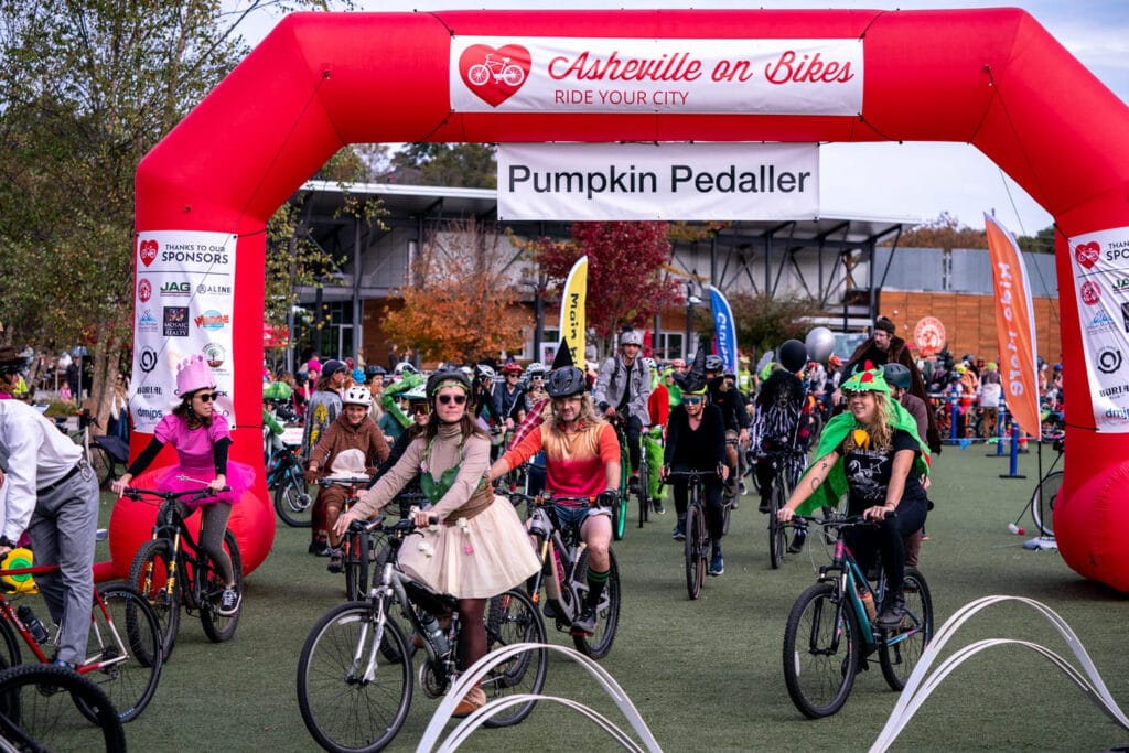 Bike riders in costumes at Pumpkin Pedaller Community Ride 2025 in Asheville