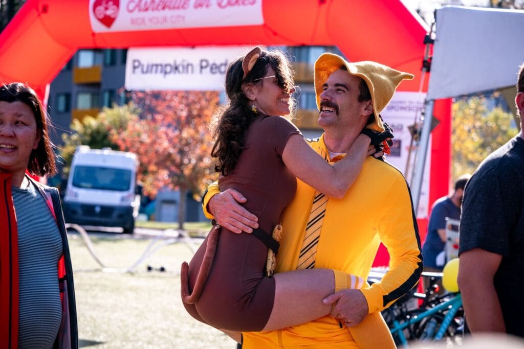 Couple in Curious George couple's costume at Pumpkin Pedaller Community Ride 2025 in Asheville