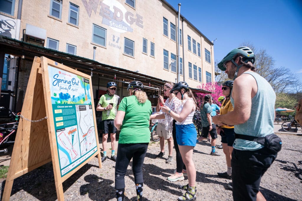 Bike riders gathered around ride maps at Spring Out 2025