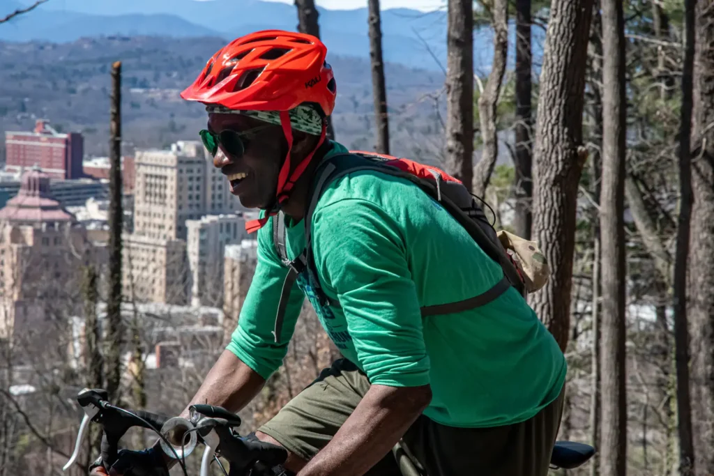 Cyclist smiling riding bicycle with downtown Asheville in background